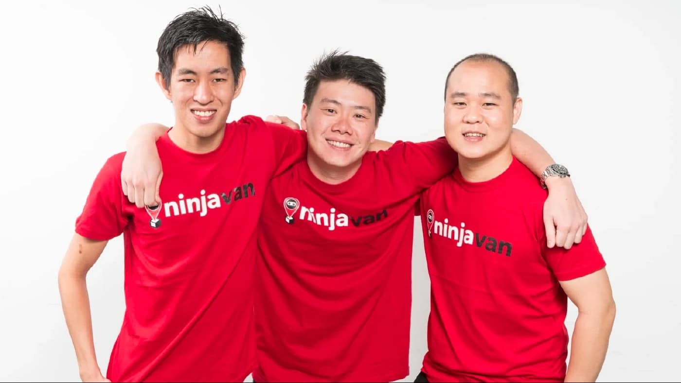 The three co-founders of Ninja Van in red company T-shirts, smiling with their arms around each other