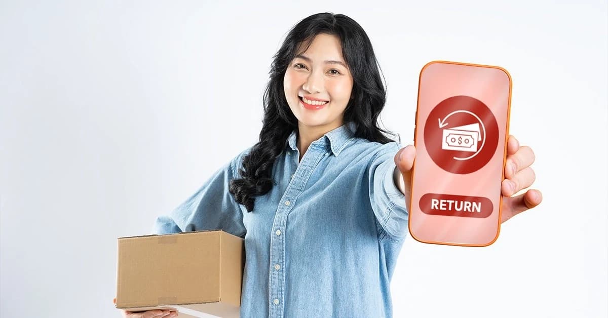A smiling woman holding a parcel and a phone showing a return option