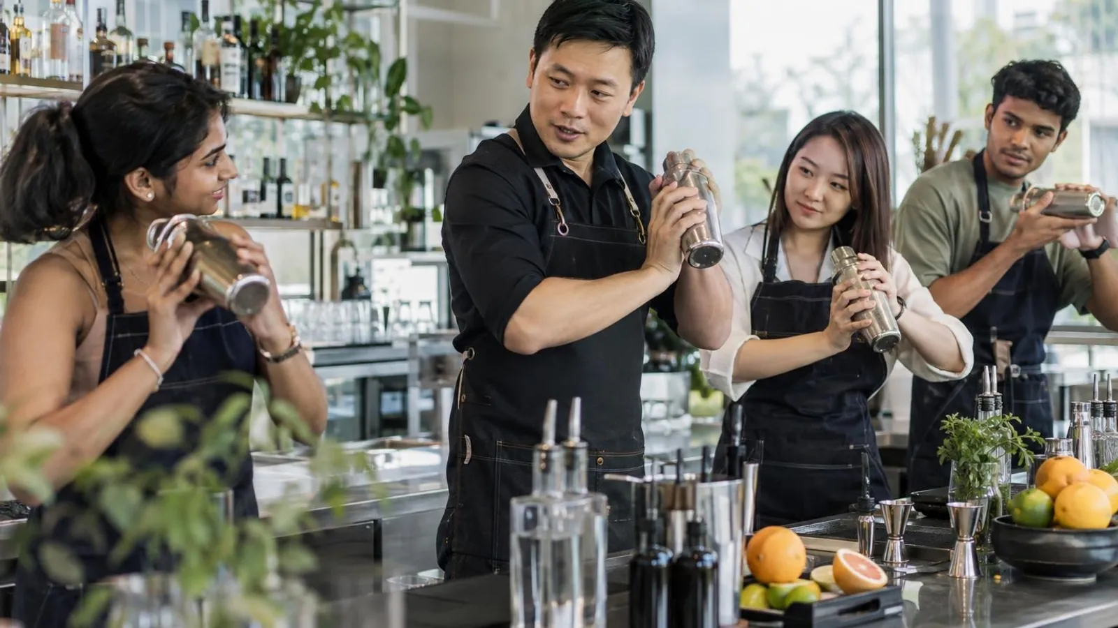 An instructor showing students how to shake a cocktail at a training bar