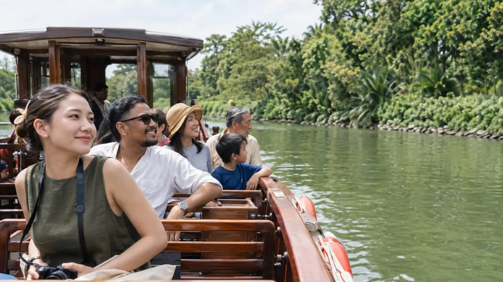 Tourists on the open deck of a traditional river boat on calm water