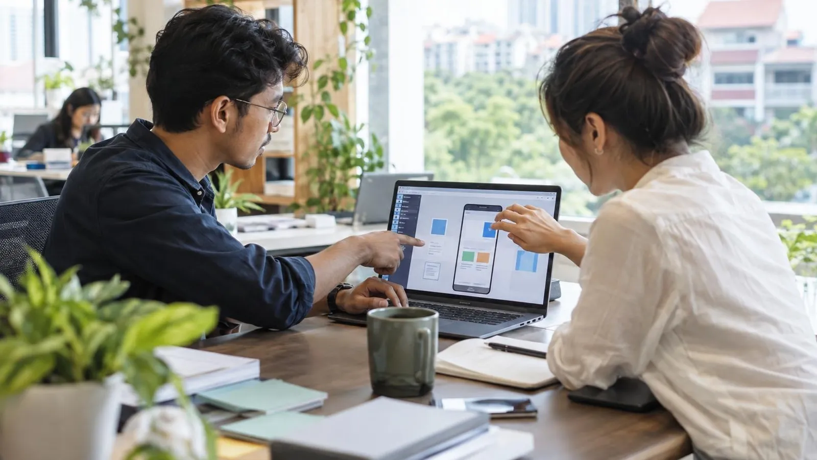 A developer and a business user building an app on a laptop in a bright modern office