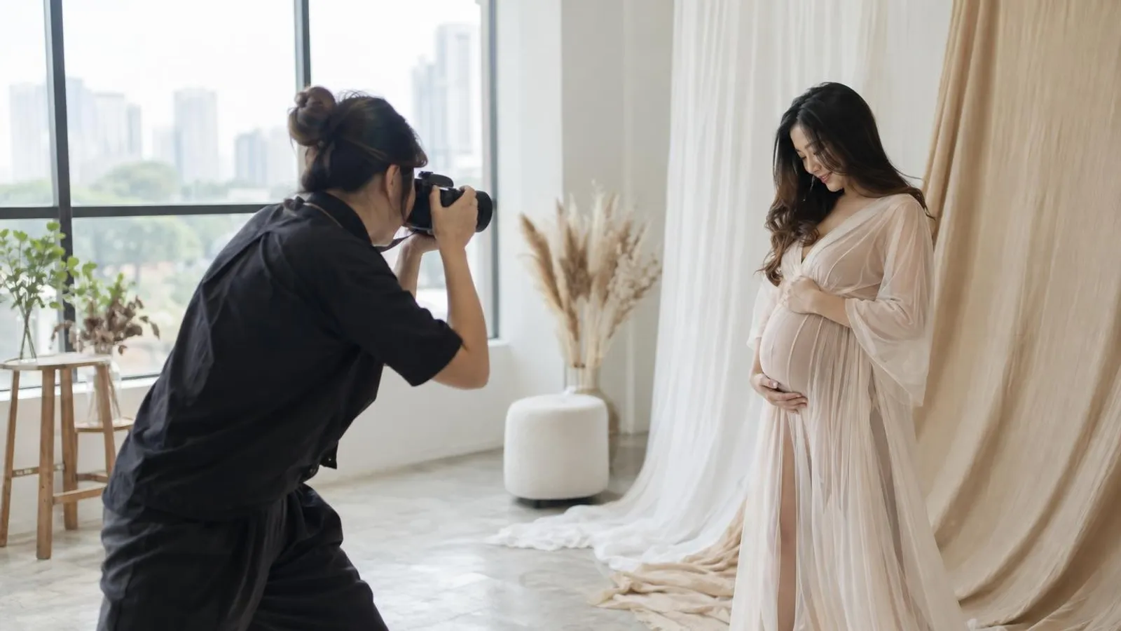 A photographer shooting a maternity bump photoshoot of a pregnant woman in a bright Singapore studio