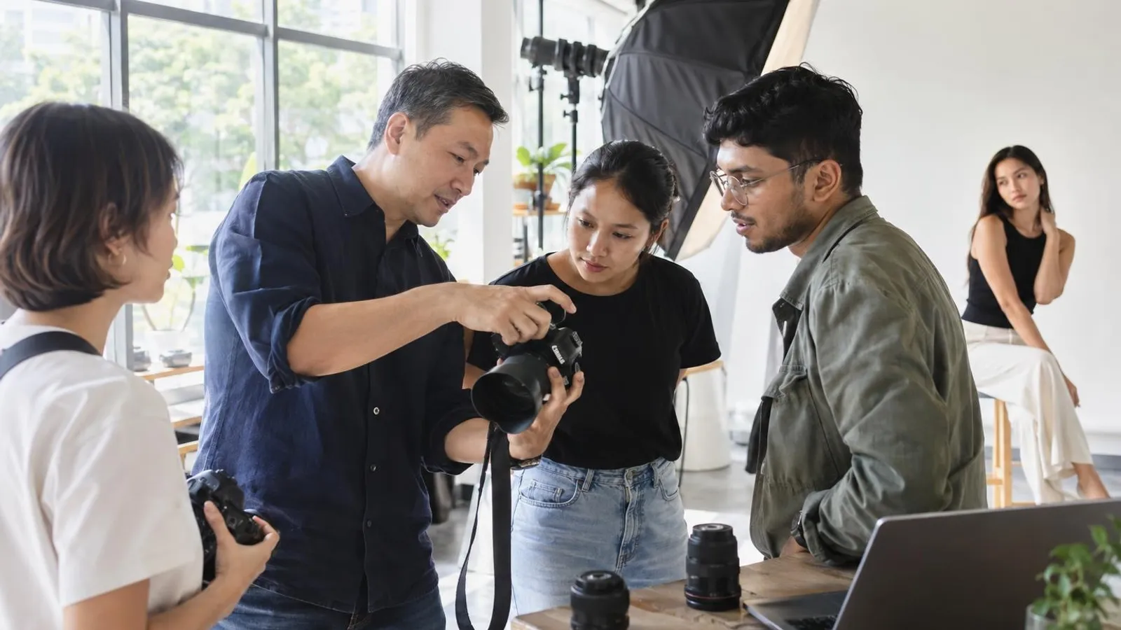 An instructor showing adult learners how to use a camera during a bright indoor photography class