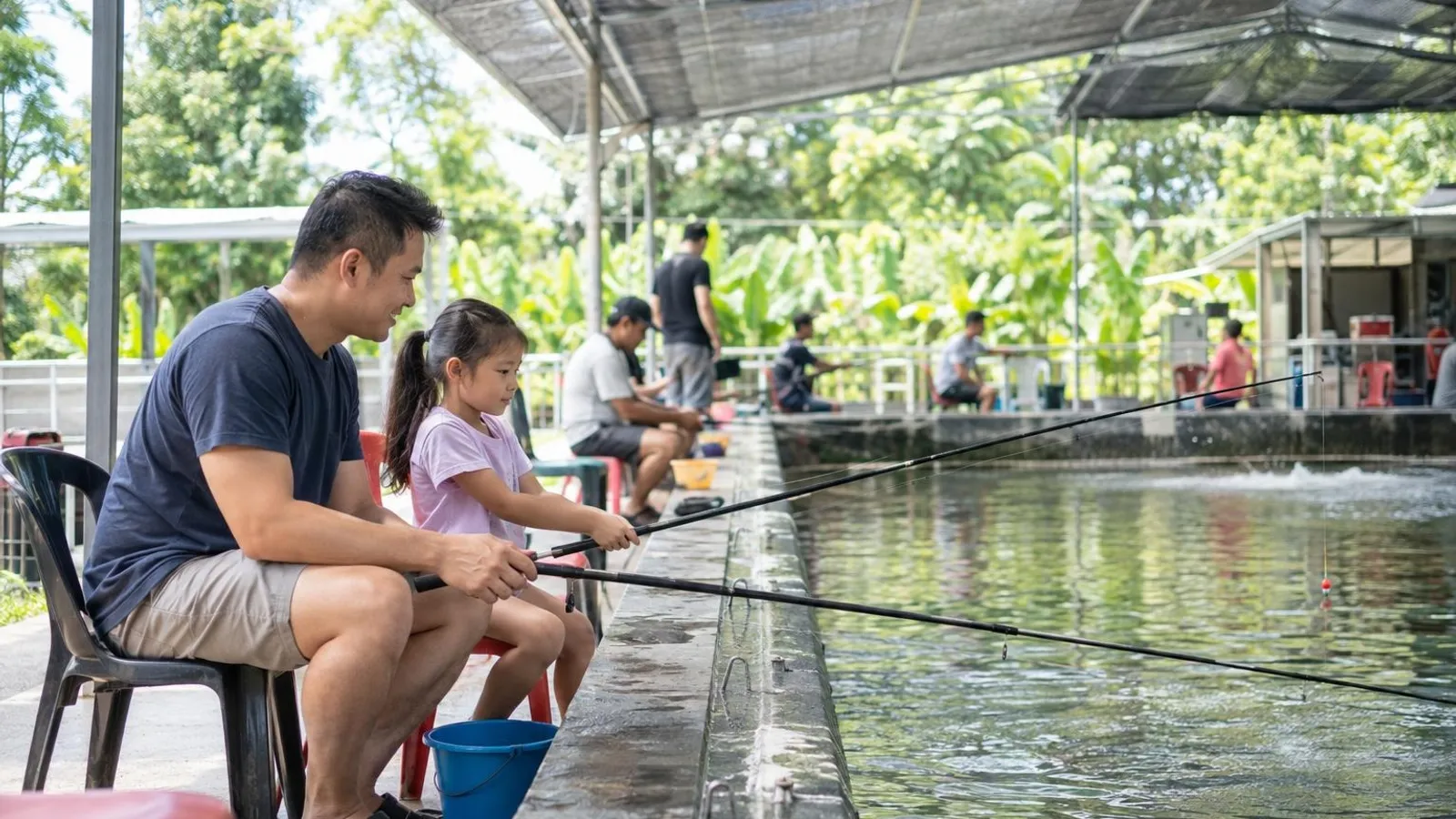 A father and daughter fishing at a prawning pond under a shaded canopy