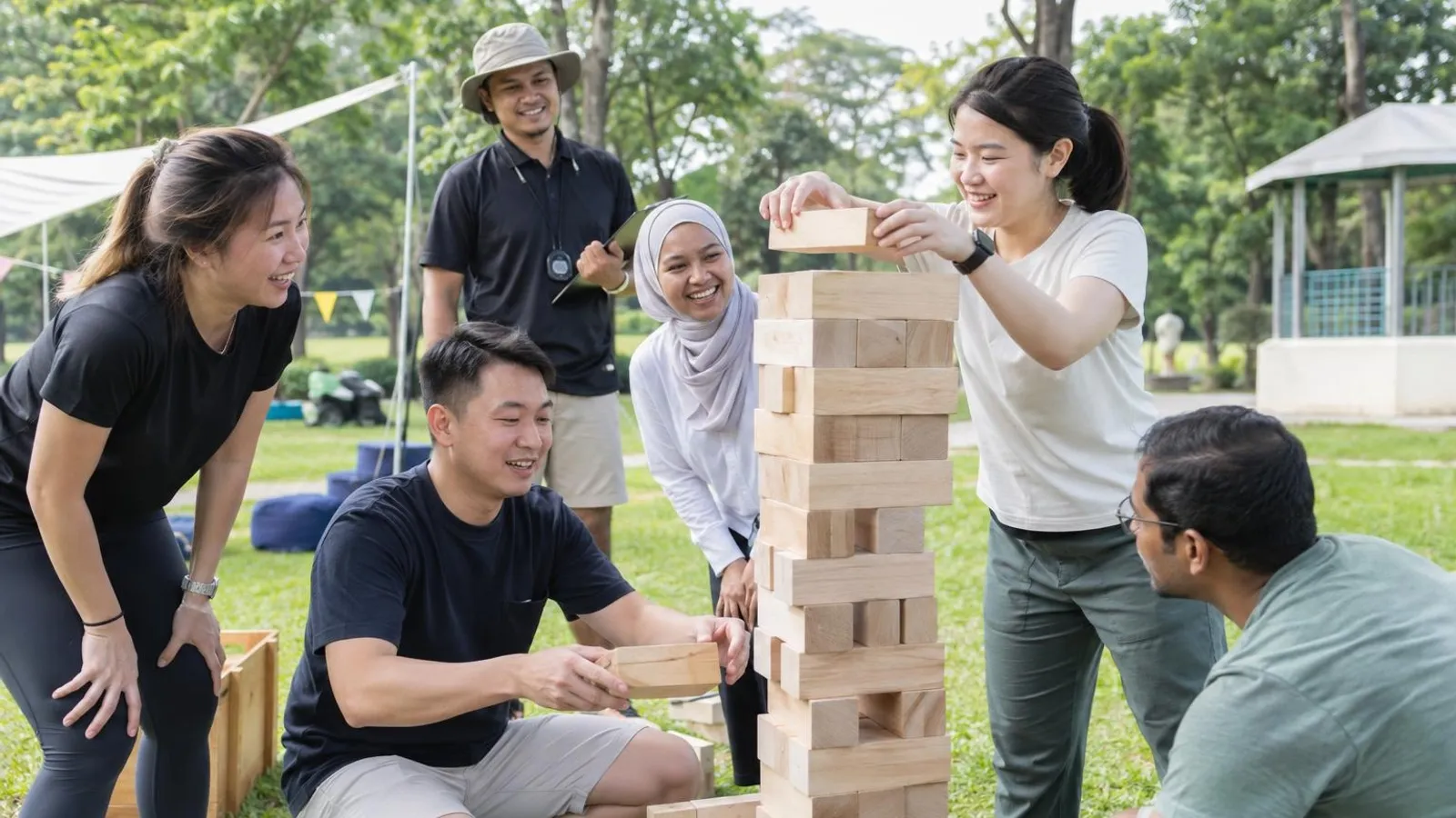 Colleagues working together to build a tall block tower at an outdoor team-building activity